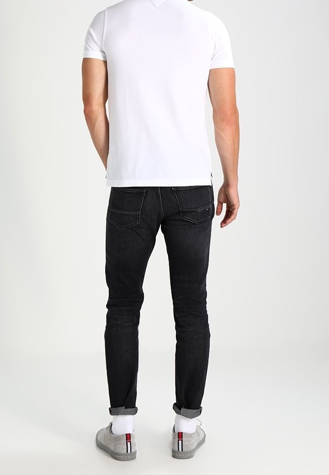 Herre slim fit hvid t-shirt parret med sorte skinny jeans. Jeansene har et klassisk fem-lomme design og subtile syninger.