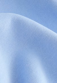 Tessuto blu chiaro con una superficie liscia, caratterizzato da un fine motivo a maglia, che drappeggia dolcemente in pieghe.