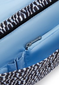 Black and white patterned fabric bag interior with light blue lining, zippered pocket, and organizational slots for items.