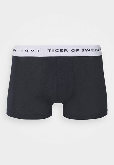 Črne bombažne boksarice s prilegajočim se dizajnom, ki vključujejo bel pas z napisom "TIGER OF SWEDEN" v črni barvi. Preprosta in gladka tekstura.