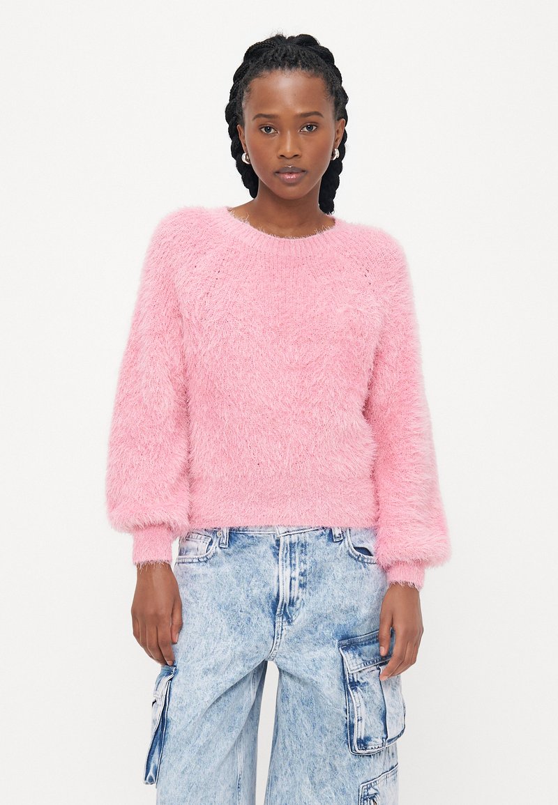 Fluffy roze trui met een ronde hals en pofmouwen, gecombineerd met lichtblauwe cargo-pantalons met zijzakken en een vervaagd textuur.
