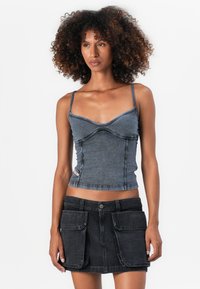 Džínová crop top ve tmavém odstínu s nastavitelnými ramínky a zakřivenými švy. Spárováno s černou džínovou sukní s předními kapsami.