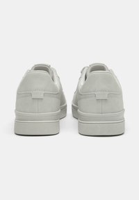 Helle graue Sneaker mit glatter Textur, runden Zehen und gepolstertem Absatz. Verfügt über subtile Stickdetails und eine flache Sohle.