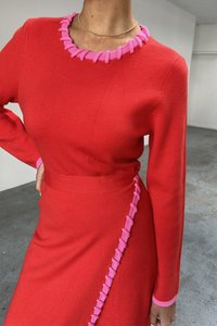 Rotes gestricktes Kleid mit einem pinkfarbenen, gerafften Ausschnitt und Akzenten an den Seiten, langen Ärmeln und einer taillierten Silhouette.