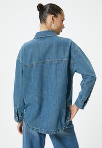 Jeansjacka i ljusblått med avslappnad passform, knäppte ärmslut och rundad nederkant. Har standardkrage och sömnadsdetalj vid ryggen.