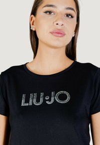 T-shirt en coton noir arborant un logo "LIU·JO" en strass scintillants sur la poitrine, col rond et manches courtes.