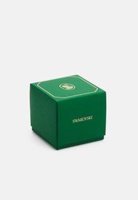 Caja de regalo verde con textura, con un logo y adornos dorados, que presenta un diseño octagonal y una base segura.