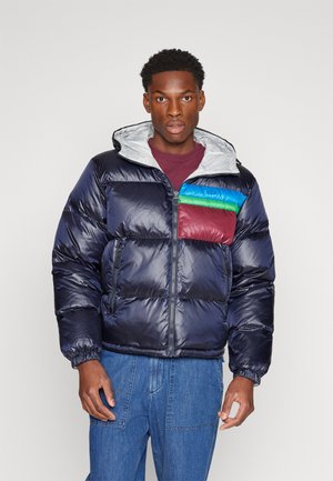 Chaqueta de plumas azul marino con capucha gris, que presenta un panel en el pecho multicolor en rojo, verde y azul. Bolsillos frontales con cremallera y puños elásticos.