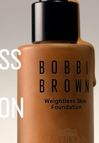 Bobbi Brown Weightless Skin Foundation i en mat brun glassflaske med svart pumpe lokk og hvit tekst på forsiden.