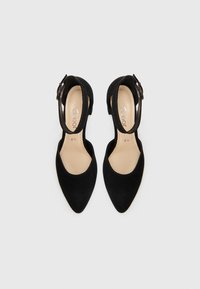 Mustade sametist slingback kontsad, millel on terav nina, reguleeritav pahkluu rihm ja madal plokknina. Siseküljel on beež vooder brändi logoga.