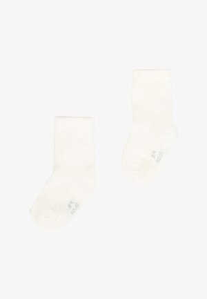 Une paire de chaussettes pour bébés blanches uni avec des indications de taille sur les semelles, présentées sur un fond blanc.