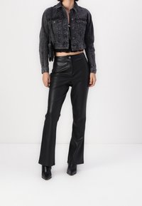 Czarna, krótka dżinsowa kurtka z srebrnymi ćwiekami, zestawiona z czarnymi, wysokimi spodniami z ekoskóry i czarnymi botkami na obcasie.