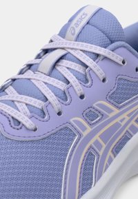 Ανοιχτό μωβ αθλητικό παπούτσι με πλέγμα, αντίθετα ανοιχτά κορδόνια και υφή σχεδίου. Διαθέτει λογότυπο και αφηρημένα κίτρινα στοιχεία.