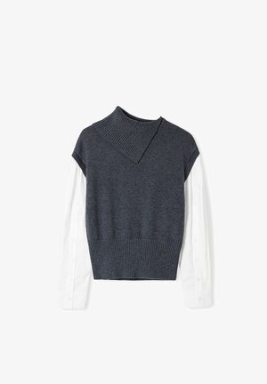 Maglione grigio a maglia con colletto a coste e design corto, indossato sopra una camicia bianca a maniche lunghe con dettagli di bottoni sulle maniche.