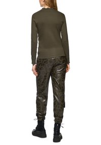 Olive green long-sleeve top with a scalloped neckline, paired with shiny black leopard print joggers and black lace-up boots.