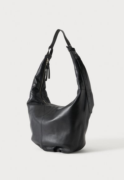 Sac à bandoulière noir en cuir, à la forme souple et décontractée, avec une longue bandoulière réglable et une fermeture zippée, sur fond clair.
