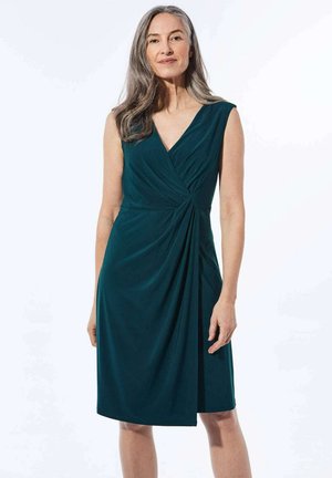 Turquoise mouwloos jurkje met een V-hals, voorzien van een twistdetail bij de taille en gedrapeerde stof die tot halverwege de dij valt. Gladde textuur.