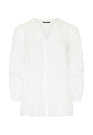 Blouse blanche à manches longues avec boutons sur le devant, col en V et détails en dentelle sur la poitrine et les manches, avec des manches légèrement bouffantes.