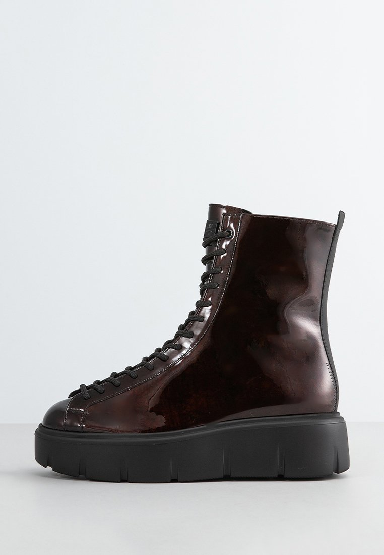 Braune Lackleder-Ankle-Boots mit schwarzen Schnürsenkeln, klobiger schwarzer Sohle und runder Zehenform. Sie haben eine glatte Oberfläche und eine Schlaufe an der Rückseite.