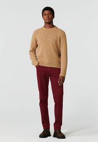 Beige wollen trui met geribbelde zoom, gecombineerd met bordeauxrode slim-fit broek en bruine veterschoenen. Eenvoudig ontwerp en effen kleuren.