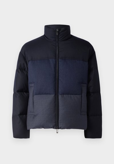 Padded jacket featuring a high collar, zip front, and a color-block design in navy and dark blue. Includes two side pockets.
