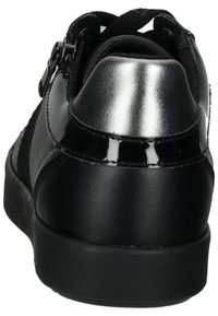 Zapatilla negra con un upper de tela texturizada, detalles de charol negro brillante, un talón plateado liso y cordones negros.