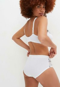 Set di lingerie bianca composto da un reggiseno con spalline regolabili e un perizoma a vita alta. Decorato con ricami floreali e una morbida texture del tessuto.