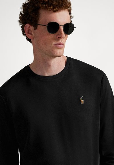 Fekete hosszú ujjú póló kerek nyakkal, bal mellrészen kis hímzett lovas logóval. Simán tapintású anyag.