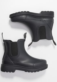 Bottes de cheville en caoutchouc noir avec des panneaux latéraux élastiques, bout rond et semelle en caoutchouc texturé dotée de rainures profondes pour une meilleure adhérence.