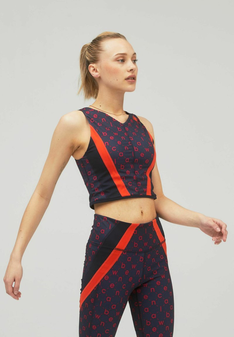 Set di abbigliamento sportivo blu navy e rosso composto da un top corto e leggings a vita alta con un motivo di testo ripetuto e audaci strisce diagonali.