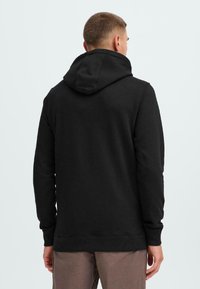 Sudadera negra con bolsillo canguro, capucha ajustable con cordón, puños y dobladillo acanalados. Textura suave y diseño minimalista.