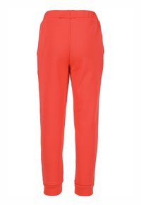 Punaiset urheiluhousut joustavalla vyötärönauhalla, kapeutettu lahjemalli ja joustavat resorit nilkoissa. Sileä kangas ilman näkyviä kuvioita.