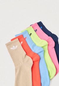 Meias caneladas de algodão em bege, coral, azul-claro, verde-neon, rosa e azul-marinho, com um logótipo branco no punho do par bege.