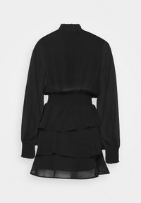 Svart långärmad klänning med hög volangkrage, elastisk midja, lager av kjol i volanger och smockade ärmar, visad bakifrån.