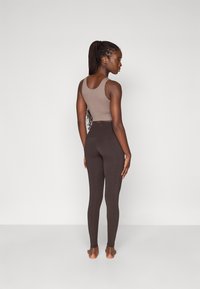Brun crop top og højtaljede leggings, begge lavet af glat stof. Leggingsene har et tætsiddende design, der giver et sømløst look.