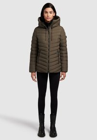 Olijfgroene pufferjack met horizontale quiltstiksels, hoge kraag, verstelbare capuchon en twee met rits afgesloten zijzakken. Draag het over zwarte leggings en laarzen.