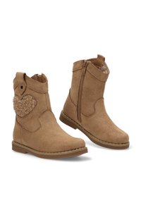 Botas de ante color topo hasta el tobillo con cierre lateral, detalle esponjoso en forma de corazón y costuras en la suela. Textura suave y tacón plano.