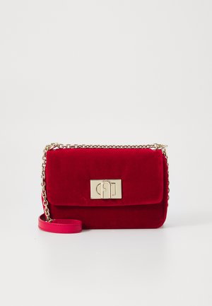 Rode fluwelen handtas met een goudkleurige sluiting, kettinghengsel en een gladde textuur. De tas heeft een gestructureerde vorm en een contrasterend roze hengsel.
