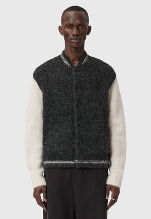 Fuzzy strikket vest i mørkegrå med cremefarvede ærmer, har en rund halskrave og et strømlinet design. Tekstureret stof og kontrasterende detaljer.