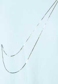 Vaaleansininen t-paita, jossa on metallinhohtoinen hopea swoosh -kuvio. Silkkinen pinta, lyhyet hihat ja pyöreä kaula-aukko.