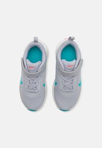 Baskets de sport grises avec des accents turquoise et un logo rouge. Tige en maille avec lacets, col rembourré et semelle en caoutchouc texturé.
