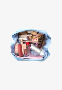 Neceser de color azul claro lleno de varios productos de belleza, incluyendo lápices labiales, brochas y un peine rosa, visto desde arriba.