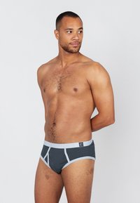 Graue Baumwollslips mit hellgrauem Bund und Akzenten. Sie verfügen über ein strukturiertes Design mit einer vorderen Tasche und kontrastierenden Steppnähten.