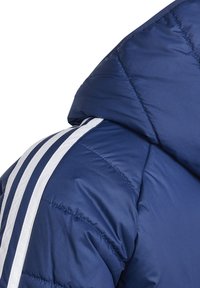 Granatowa kurtka puchowa z kapturem, pikowanym materiałem i wyraźnymi białymi paskami na ramionach dla dodatkowego akcentu wizualnego.