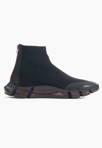 Baskets montantes style chaussette en maille noire avec semelle segmentée flexible et fermeture éclair arrière.