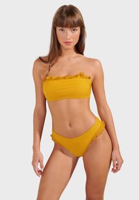 Yellow bikini set with ruffled trim. Strapless top and high-waisted bottom. Smooth texture, simple design, and vibrant color.