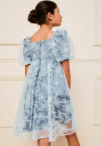 Hellblaues Kleid mit durchsichtigen Puffärmeln, besticktem Blumenmuster und tailliertem Oberteil. Verfügt über einen quadratischen Rücken und einen fließenden Rock.
