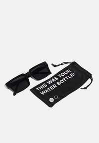 Ochelari de soare pătrați din plastic negru cu lentile întunecate, alături de un pachet cu șnur negru. Pachetul are un text alb: "ACEASTA A FOST STICLA TA DE APĂ!"
