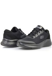 Scarpe sportive nere con una tomaia in mesh testurizzato, sovrapposizioni lisce e una suola imbottita e testurizzata. Presentano dettagli con logo sui lati e sulla linguetta.