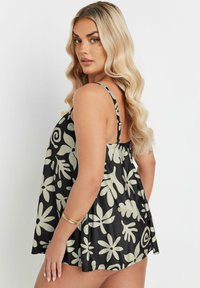 Svart blommig linne med ljusbeige blommor och bladmönster. Tillverkat av lättviktsmaterial med tunna justerbara axelband och en lös passform.